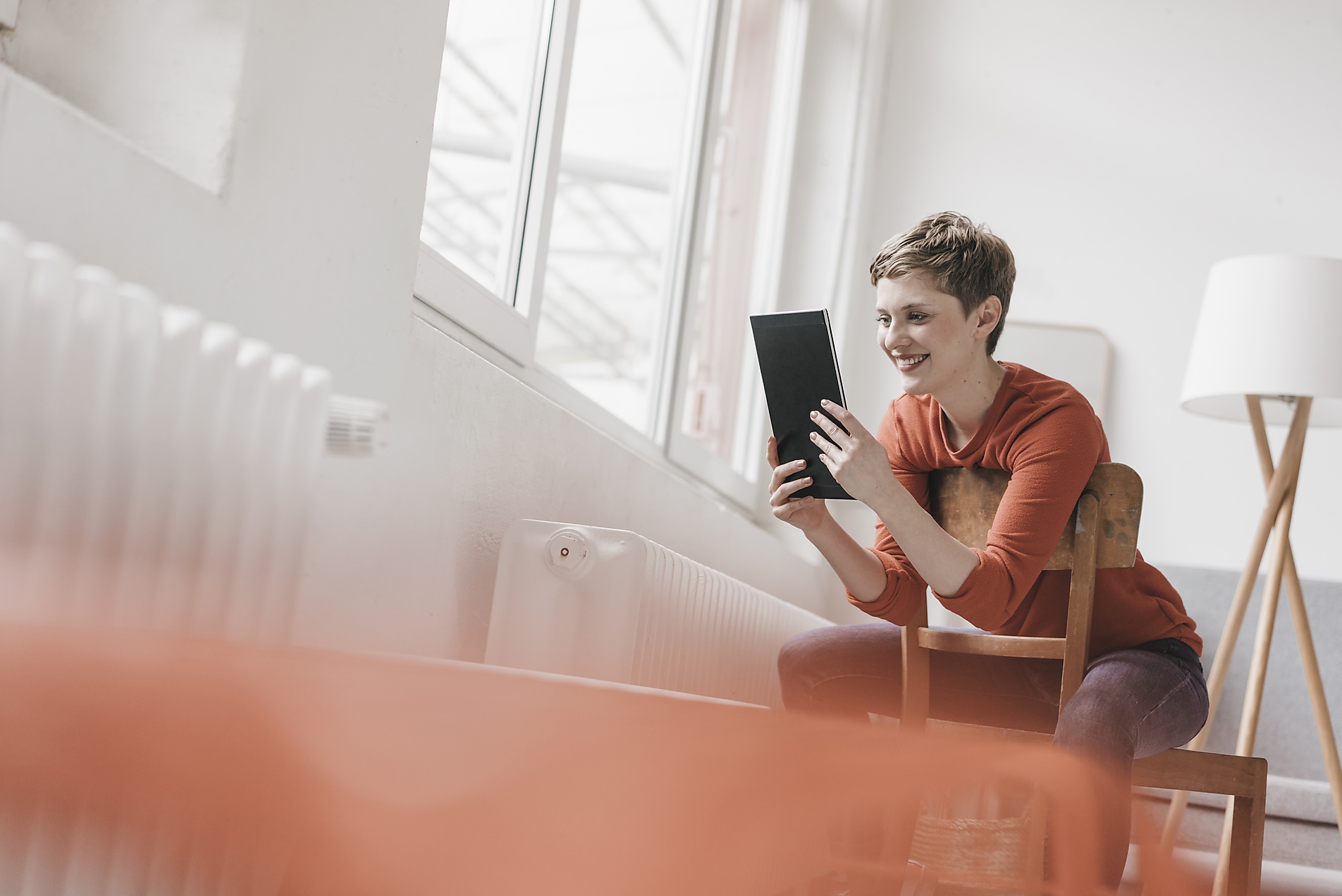 Frau mit Tablet an einer Heizung