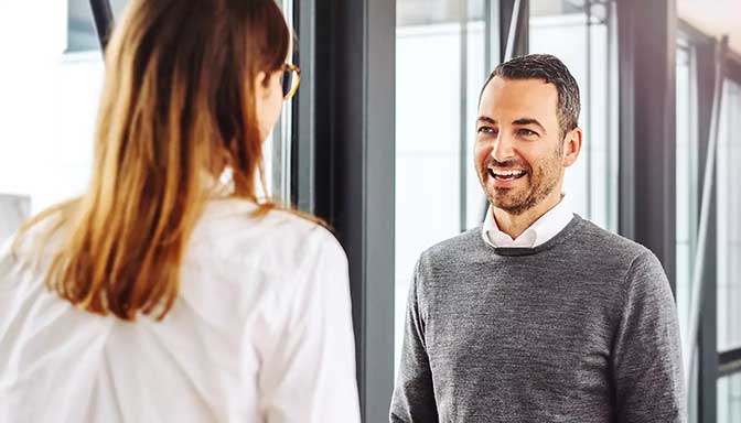 Eine Frau begrüßt einen Mann im Büro