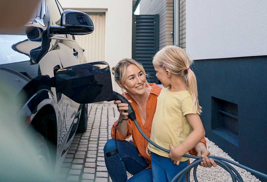 Eine Mutter und Tochter laden ein E-Auto