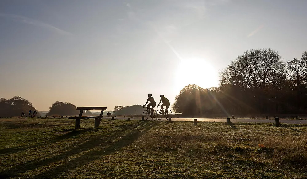 Zwei Fahrradfahrer in der Landschaft bei Sonnenuntergang.