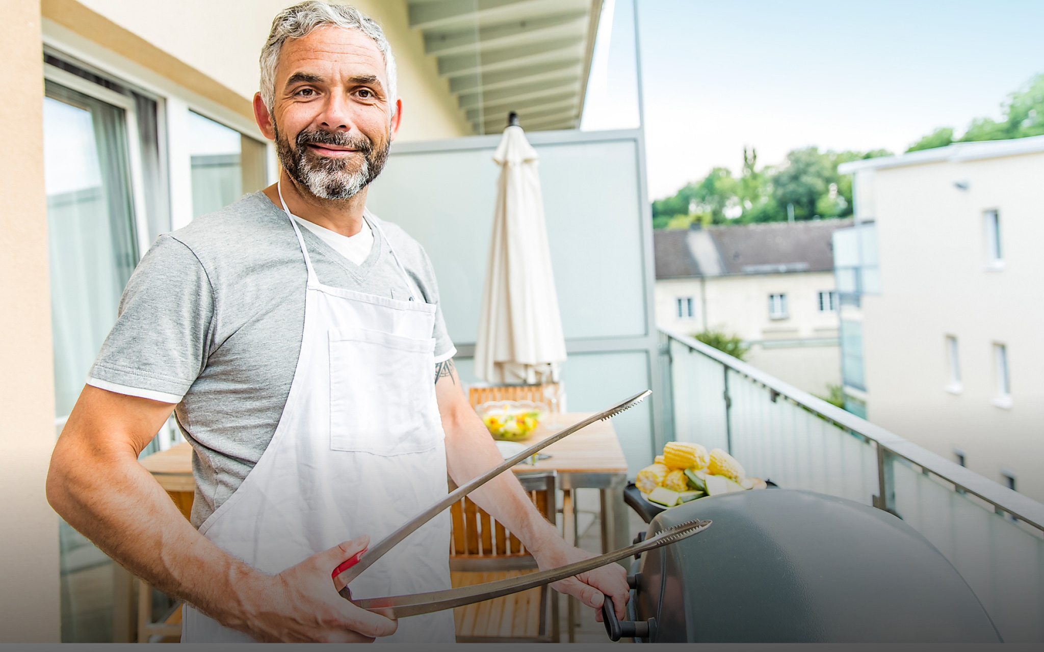 Mann grillt auf dem Balkon und lächelt