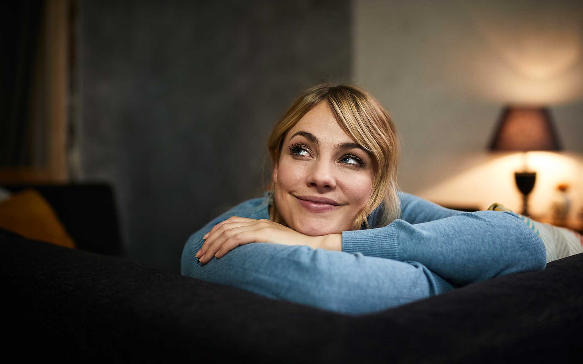 Portrait einer lächelnden Frau, die sich auf dem Sofa entspannt