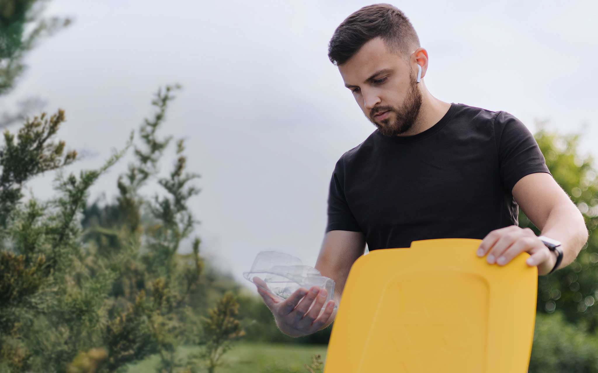 Mann wirft eine Verpackung in die Wertstofftonne
