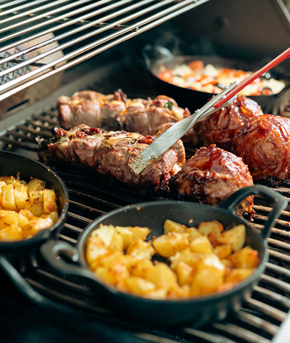 Grillrost mit Fleisch und einer Schüssel Kartoffeln