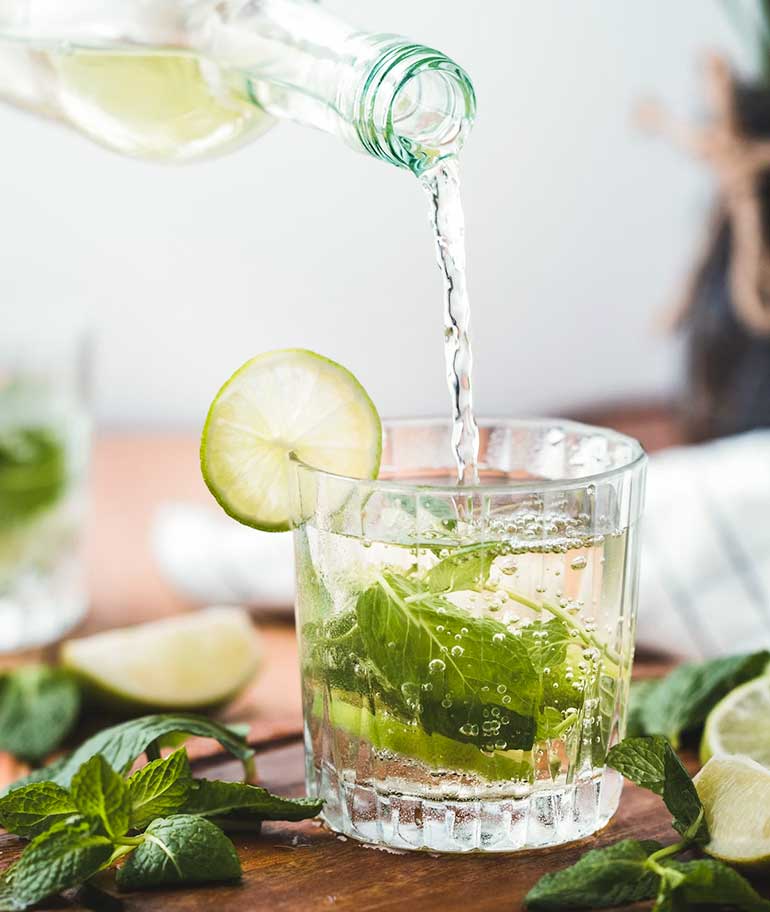 Limonade wird in ein Glas mit Limetten gegossen