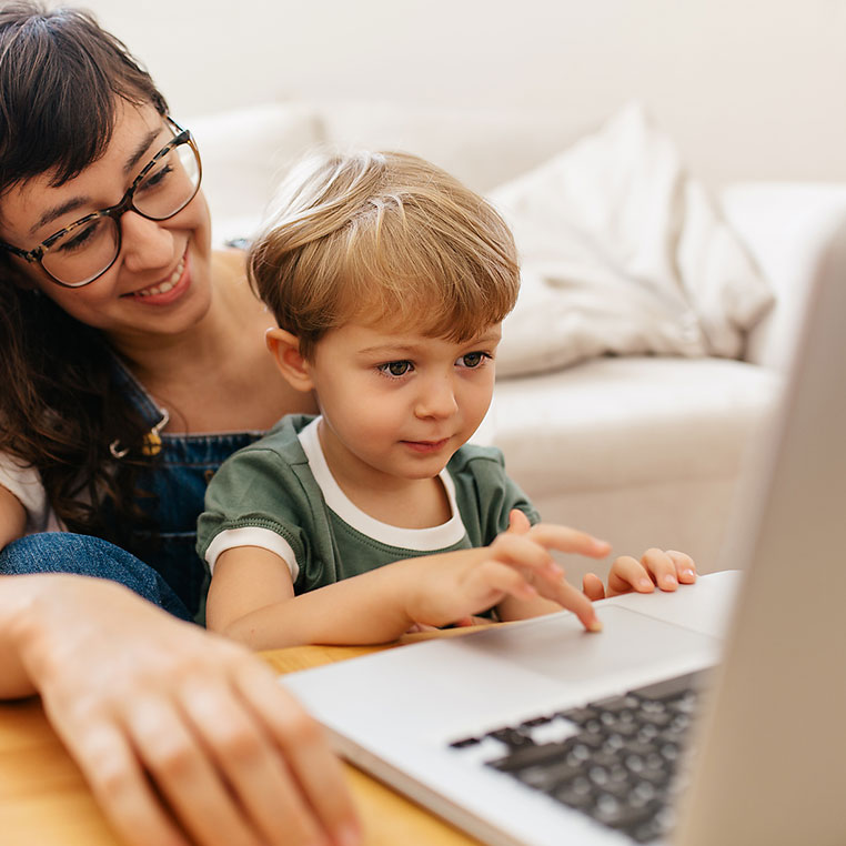 Mutter sitzt mit kleinem Sohn vorm Computer