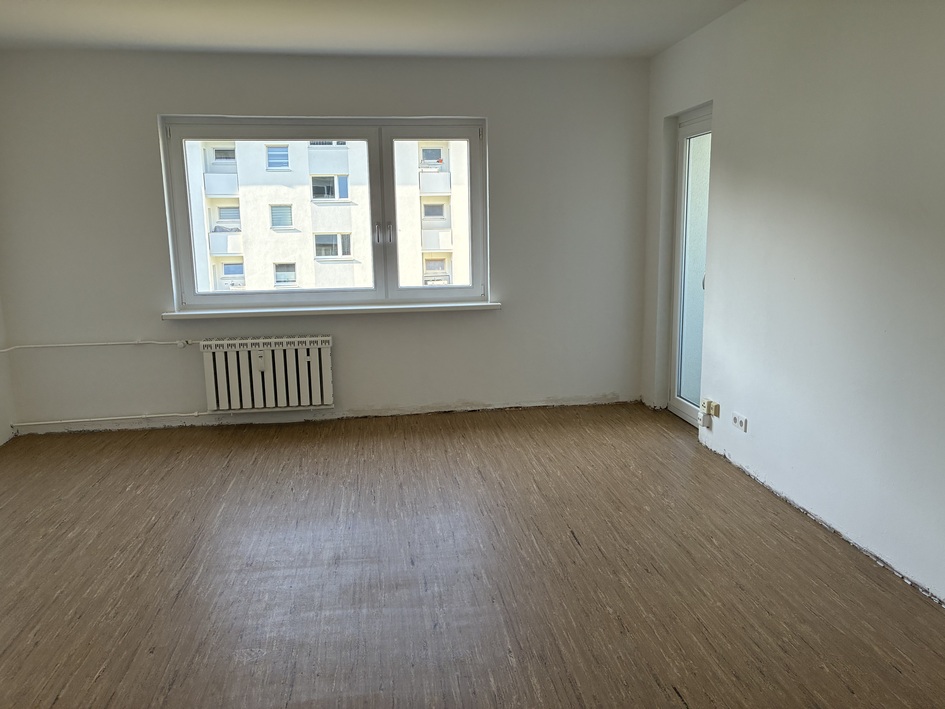 Leerer Raum mit Holzfußboden, Fenster, Heizkörper und Zugang zu Balkon oder Terrasse.