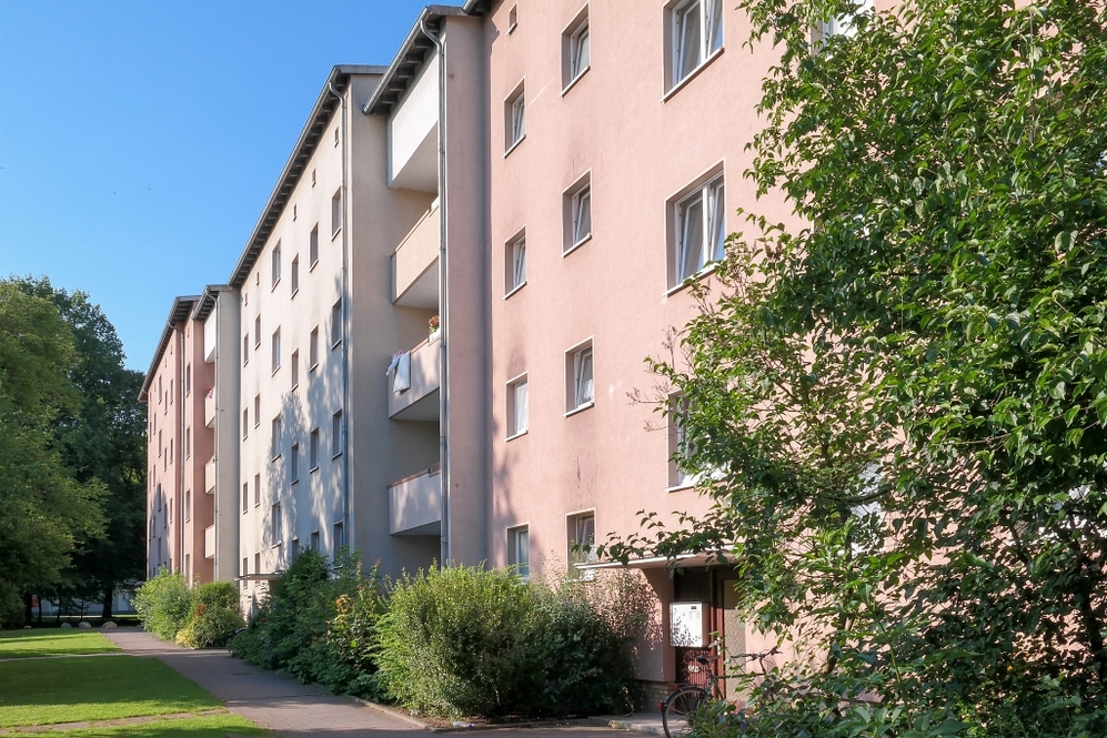 Mehrstöckige Wohngebäude mit Balkonen und Grünflächen bei sonnigem Wetter.