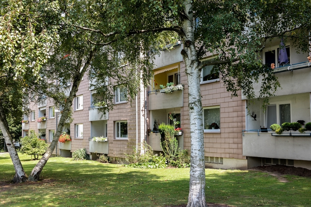 Mehrfamilienhaus mit Balkonen und gepflegtem Grün in ruhiger Wohnanlage.