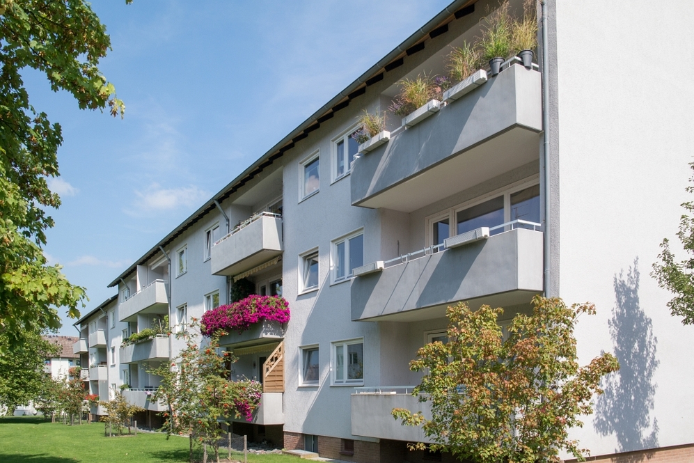 Mehrstöckiges Wohngebäude mit Balkonen und gepflegtem Grün im Vordergrund.