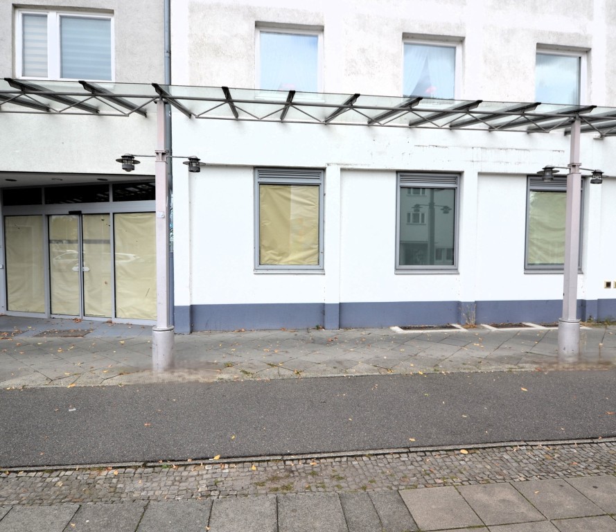 Leerstehende Ladenfläche mit verhangenen Fenstern und Eingangsbereich in Wohngebäude.