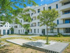 Moderner Mehrfamilienwohnkomplex mit Grünflächen und Spielbereich im Innenhof.