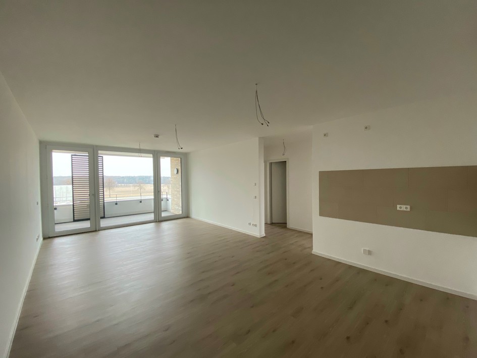 Helle, offene Wohnung mit großem Fensterfront und Zugang zu Balkon, moderner Bodenbelag.